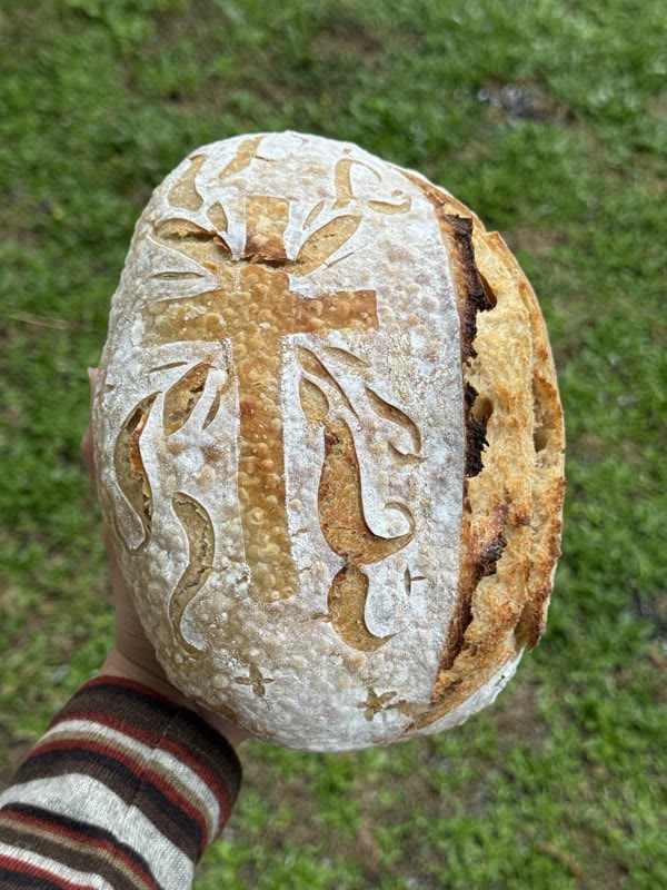 Sourdough loaf hand-scored with a cross and wheat design