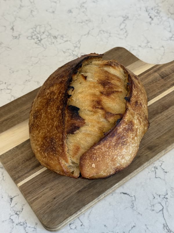 A golden sourdough boule resting on a wooden board