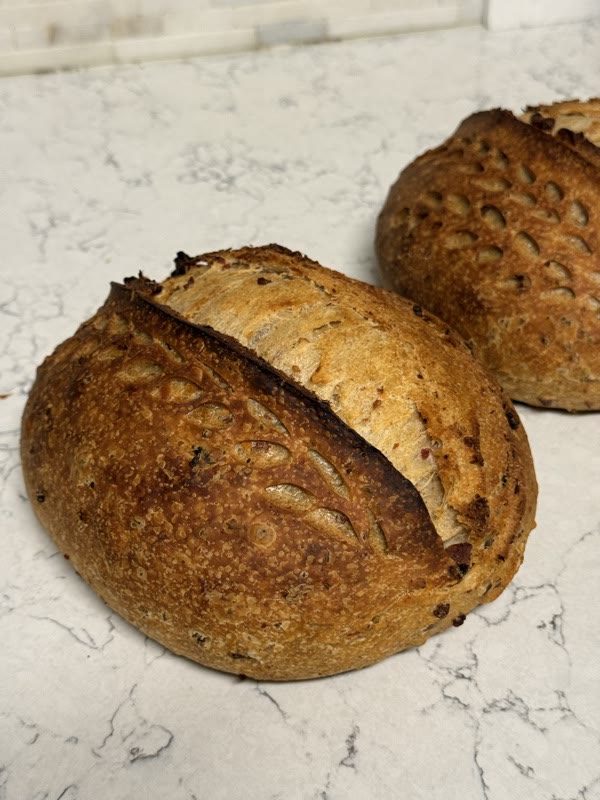 Two jalapeño cheddar loaves with hand-scored crusts