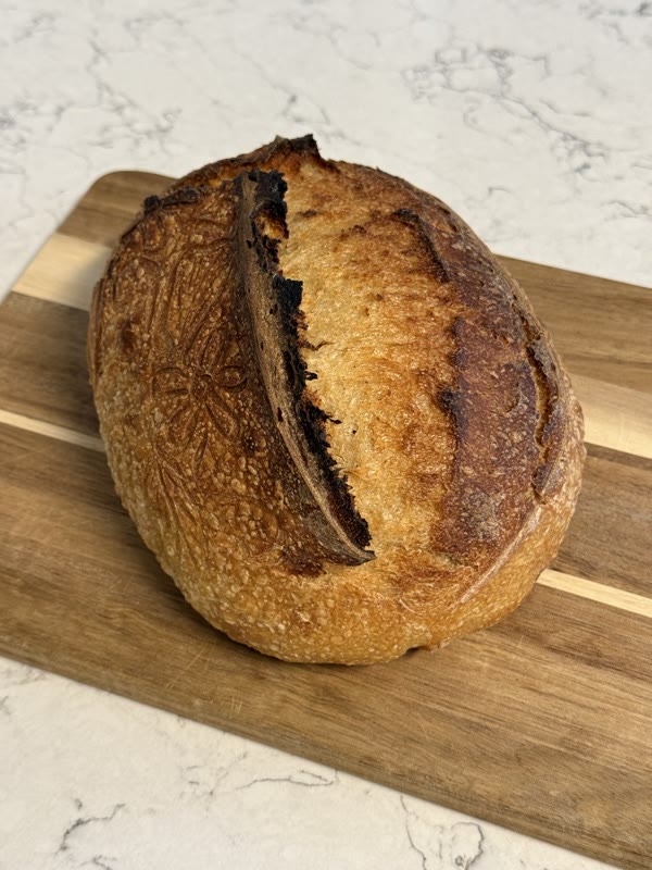 Sourdough loaf with a floral stencil and a deep golden ear